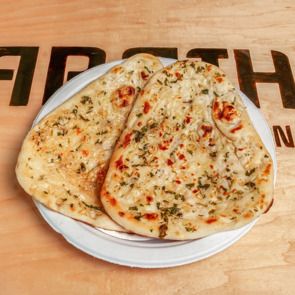 Two pieces of golden-brown garlic naan bread, topped with herbs, on a white plate.